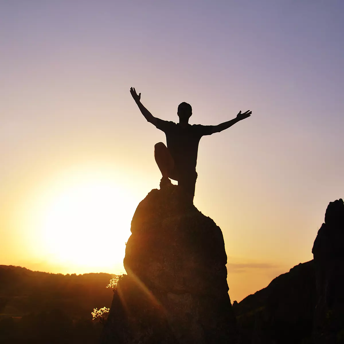 Man on top of mountain with his hands raised in celebration